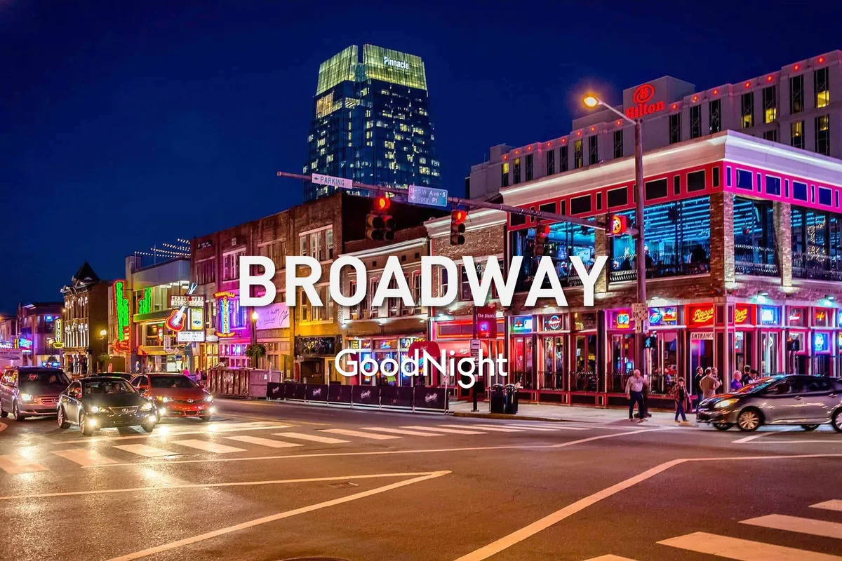 This vibrant exterior shot captures the neon-lit Broadway sign, buzzing street activity with cars and pedestrians, and the lively energy of downtown Nashville at night. The scene immediately evokes the excitement and music-centric nightlife the city is known for.