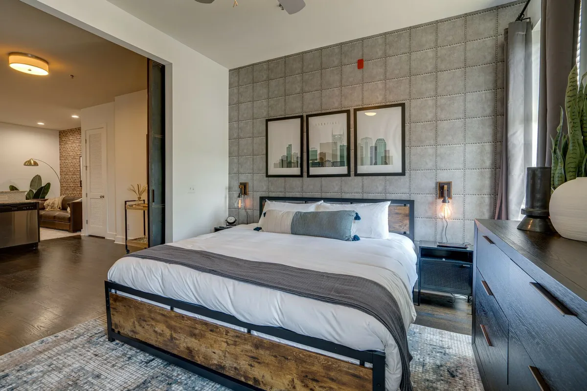 A tranquil bedroom scene with a king-sized bed, elegant wall art, nightstands on either side, and gentle morning light filtering through window curtains for a peaceful, relaxing ambiance.